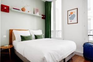 um quarto com uma grande cama branca e uma janela em Edgar Suites Louvre - Saint-Honoré em Paris