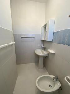 a white bathroom with a sink and a toilet at Villette di Cala Creta in Lampedusa