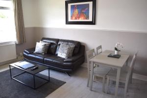 sala de estar con sofá de cuero negro y mesa en Kelpies Serviced Apartments - Wallace en Falkirk