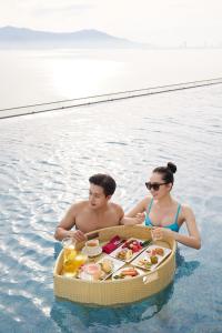 un homme et une femme dans l'eau avec un plateau de nourriture dans l'établissement Da Nang - Mikazuki Japanese Resorts & Spa, à Đà Nẵng