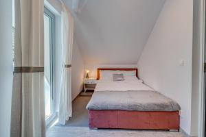 a small bedroom with a bed and a window at PROFIL Family House in Pogorzelica