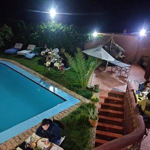 un grupo de personas sentadas alrededor de una piscina por la noche en Riad Gabsi Dades, en Boumalne