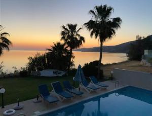 un grupo de sillas sentadas junto a una piscina en Kallinousa Beach Villa, en Pomos