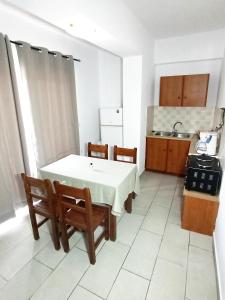 Villa Pouliezos Apartments في اليكاناس: مطبخ مع طاولة وكراسي ومغسلة
