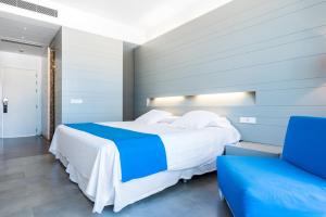 sypialnia z dużym łóżkiem i niebieskim krzesłem w obiekcie Hotel Spa Calagrande Cabo de Gata w mieście Las Negras