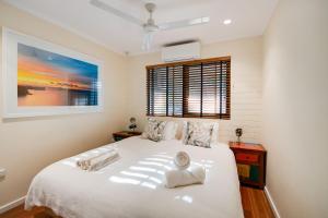a bedroom with a white bed and a window at Tropical Boho Nightcliff Casinha 3BR 1.5BR in Nightcliff