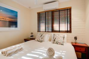 a bedroom with a large white bed and a window at Tropical Boho Nightcliff Casinha 3BR 1.5BR in Nightcliff +17 photos