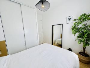 a bedroom with a white bed and a mirror at Cambo T1 Bis avec Terrasse pour 2, Parking - FR-1-495-105 in Cambo-les-Bains +9 photos