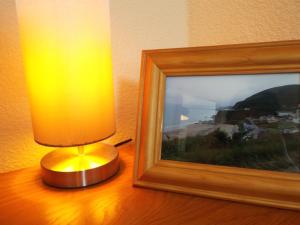 a lamp sitting on a table next to a picture at Cosy Cottage In Cardigan in Cardigan