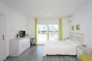 a white bedroom with a bed and a television at Port 27 in Empuriabrava