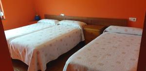 three beds in a room with orange walls at Alojamientos Fermín in Cangas de Onís