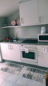 a kitchen with white cabinets and a stove and a sink at Ático encantador... in A Coruña