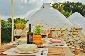 a table with wine glasses and a bottle of wine at Trulli Vulés in Ostuni