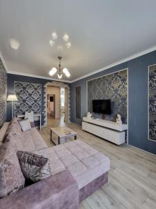 a living room with a couch and a flat screen tv at 2x SuperLUX Arbat Chehova-Kirova 55 in Ustʼ-Kamenogorsk