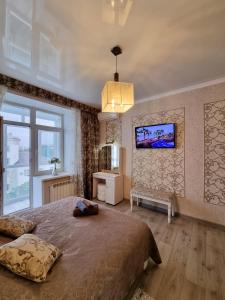 a bedroom with a large bed and a tv on the wall at 2x SuperLUX Arbat Chehova-Kirova 55 in Ustʼ-Kamenogorsk +15 photos