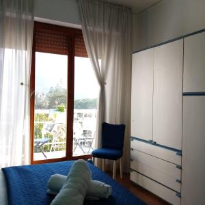ein Schlafzimmer mit einem Bett, einem Stuhl und einem Fenster in der Unterkunft Casa Rosamarina in Mondello