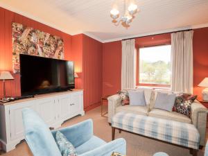 a living room with red walls and a flat screen tv at Smithy Cottage in Achnasheen