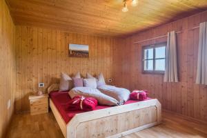 1 dormitorio con 1 cama en una pared de madera en Almhütte Jägerrast, en Verano