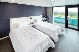 two beds in a hotel room with a large window at SN Hotel Daecheon in Boryeong +61 photos