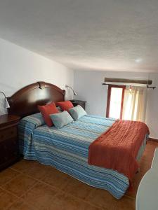 a bedroom with a large bed with blue and red pillows at La Buhardilla de Torrecillas in El Bosque