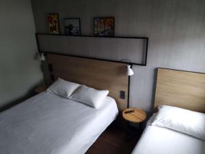 a hotel room with two beds and a night stand at ibis Bayonne Centre in Bayonne
