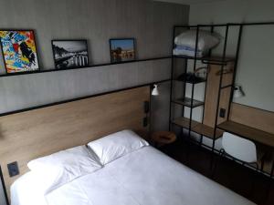 - une chambre avec un lit blanc et une étagère avec des photos dans l'établissement ibis Bayonne Centre, à Bayonne