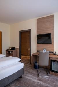 a hotel room with a bed and a desk and a tv at Hotel Kastanienhof in Erding