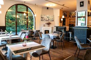 a restaurant with tables and chairs and a fireplace at Hotel Kastanienhof in Erding
