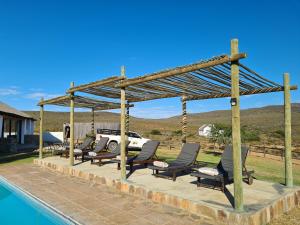 un grupo de sillas sentadas bajo un pabellón junto a una piscina en African Game Lodge, en Montagu