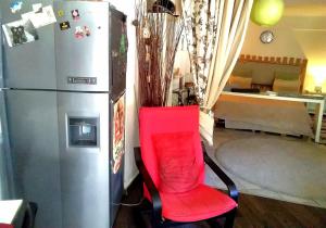 a red chair next to a refrigerator in a room at LOBBY comfort studio in Thessaloniki