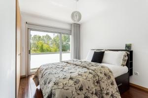 1 dormitorio con cama y ventana grande en ALTIDO Sleek House w/Balcony & 2 Terraces in Porto, en Maia
