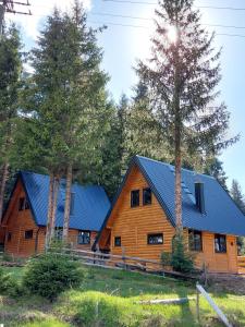 a log cabin with a blue roof and two trees at Gorske Vile Jahorina in Jahorina