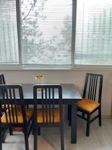 a dining room table and two chairs with windows at Cosy Apartment on an amazing location! in Skopje
