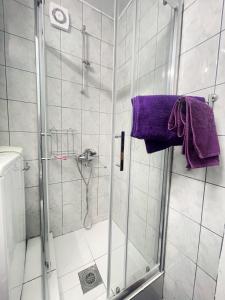 een badkamer met een douche en een paarse handdoek bij Cosy Apartment on an amazing location! in Skopje