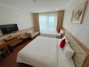 ein Hotelzimmer mit einem großen Bett und einem TV in der Unterkunft Serene Beach Danang Hotel in Đà Nẵng