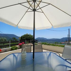 a table with a white umbrella on a balcony at Zoggos Apartment in Áyios Pétros