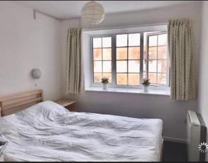 Un dormitorio con una cama blanca y dos ventanas. en Great price, lovely comfy flat.2 mins from the sea, en Lyme Regis