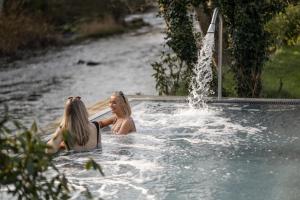 巴利米納的住宿－Galgorm，两个女人坐在喷泉旁的热水浴缸里