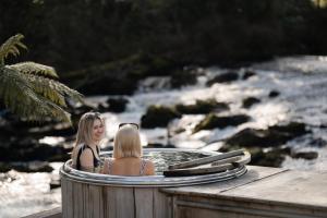 two women sitting in a hot tub next to a river at Galgorm in Ballymena