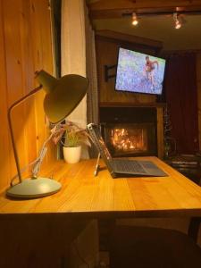 a desk with a laptop and a lamp and a television at Snow Bunny Cottage, Pets Welcomed! in Green Valley Lake