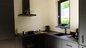 a kitchen with a black counter and a window at The Black Oak - Luxe bungalow met prive sauna in Voorthuizen
