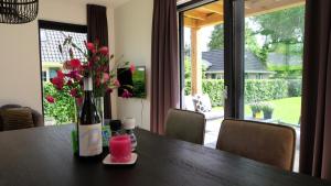 een tafel met een fles wijn en bloemen erop bij The Black Oak - Luxe bungalow met prive sauna in Voorthuizen