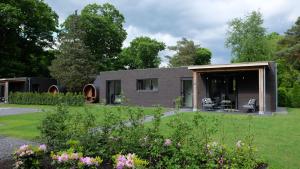 una casa en un jardín con flores en The Black Oak - Luxe bungalow met prive sauna, en Voorthuizen
