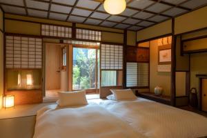 a bedroom with a large bed in a room with windows at The Machiya Kamiumeya in Kyoto