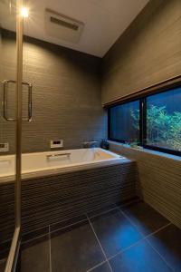 een grote badkamer met een bad en een raam bij The Machiya Kamiumeya in Kyoto