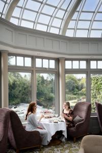 twee vrouwen die rond een tafel zitten in een kamer met ramen bij Galgorm in Ballymena