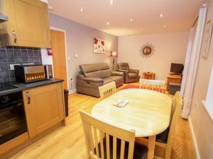 a kitchen and living room with a table and a couch at 9 The Oakleys in Porthmadog