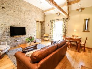 a living room with a leather couch and a stone wall at Golwg Las in Llanwrda