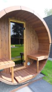 a wooden sauna with a bench and a window at The Black Oak - Luxe bungalow met prive sauna in Voorthuizen