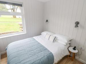 ein weißes Schlafzimmer mit einem Bett und einem Fenster in der Unterkunft Saltwater in Haverfordwest
